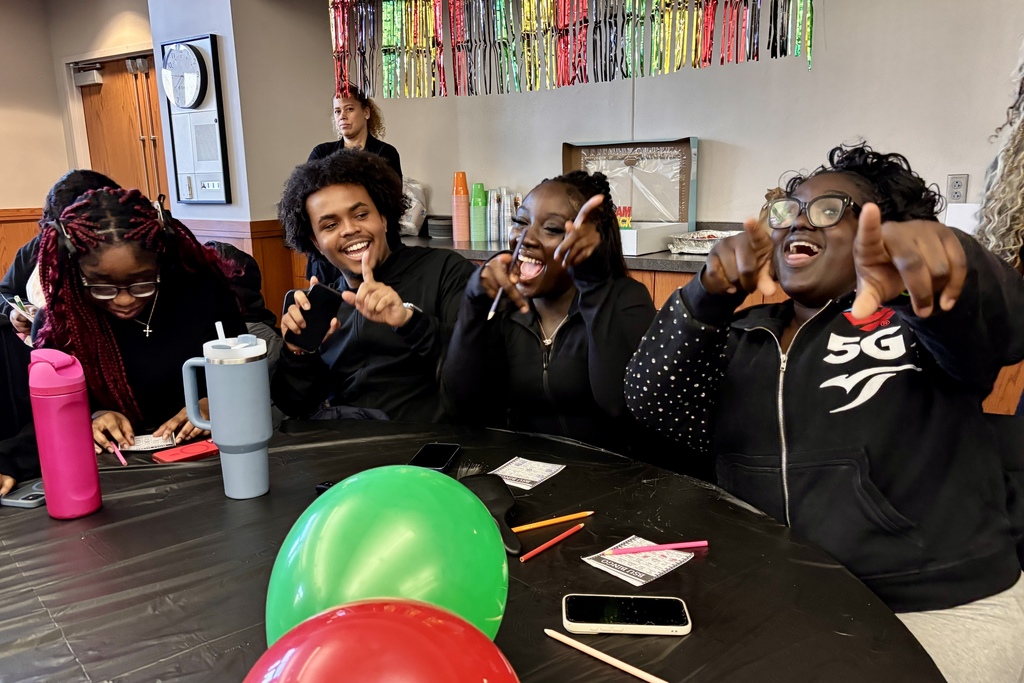 A group of young people are gathered around a table, laughing and playing a game of bingo.