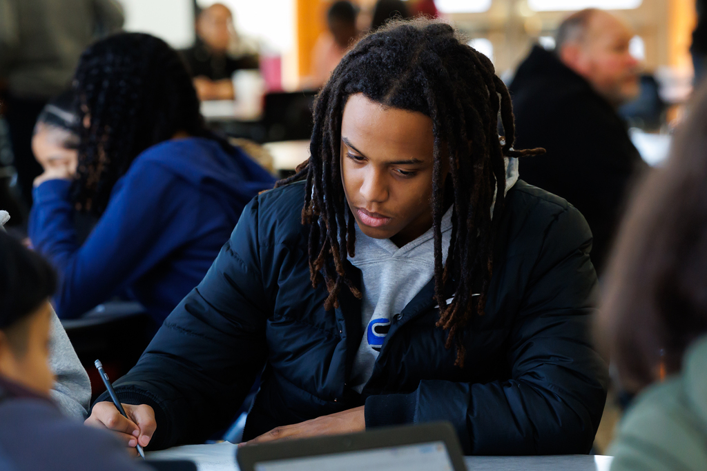 A student writes a letter during an activity. 