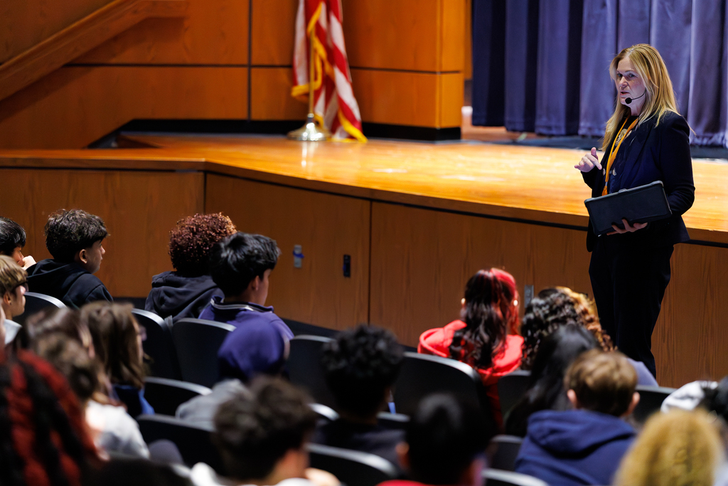 Students listen to an adult in an auditorium during an info session.