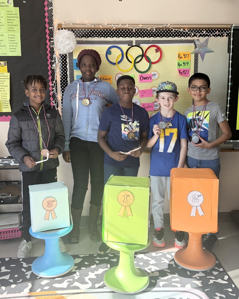 Five students stand behind podiums holding prizes after a science experiment.