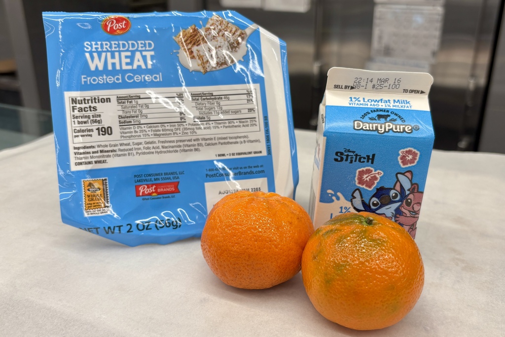 A box of Post Shredded Wheat Frosted Cereal, two tangerines, and a carton of DairyPure 1% Lowfat Milk with Stitch characters.