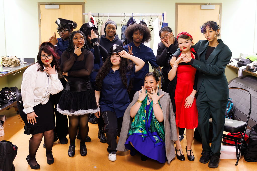 A group of young people in various costumes, some in police-inspired outfits, pose for a photo.