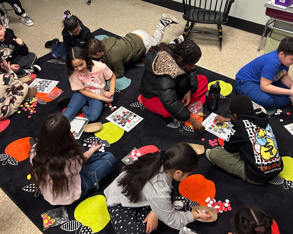 A group of students work together on a classroom rug.