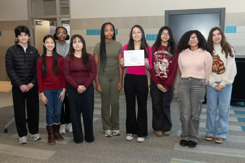 The editors of The Apricot Journal stand side-by-side for a photo, one student is holding a certificate.