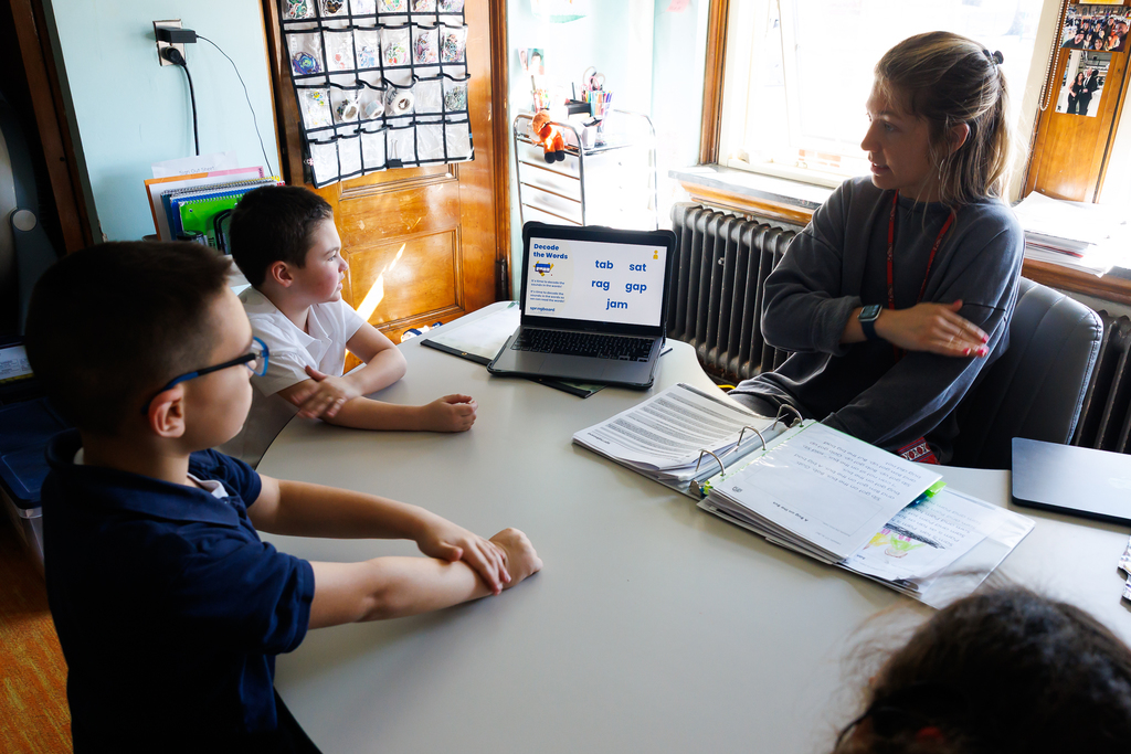 Two students and a teacher engaged in reading activites.