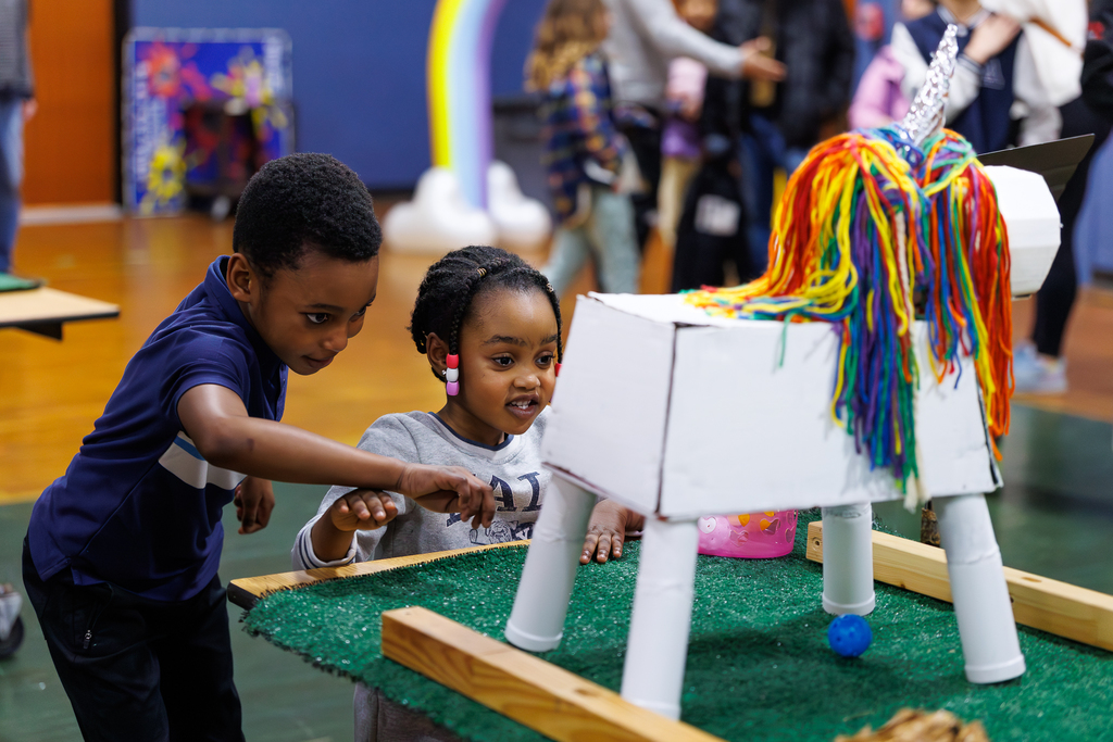Two young students play during a mini-golf event.