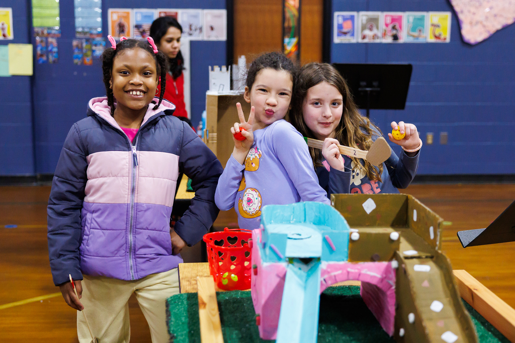 Three young students smile and pose for a photo.