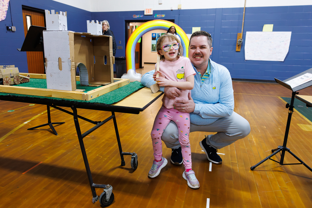 A dad and their young student smile for a photo together.