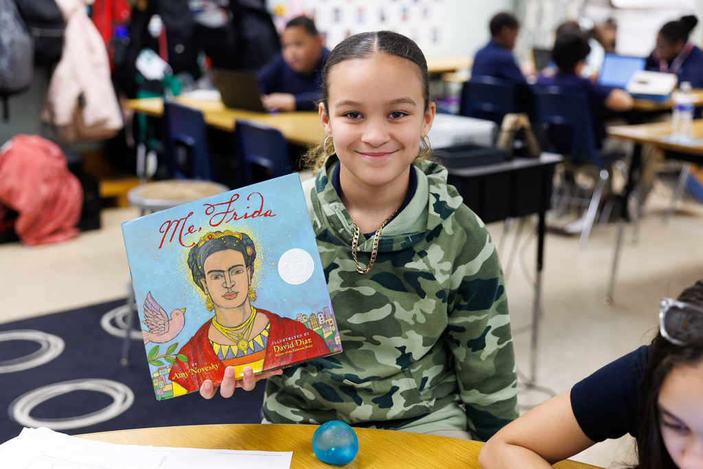 A student holds up a book about Frida Kahlo.