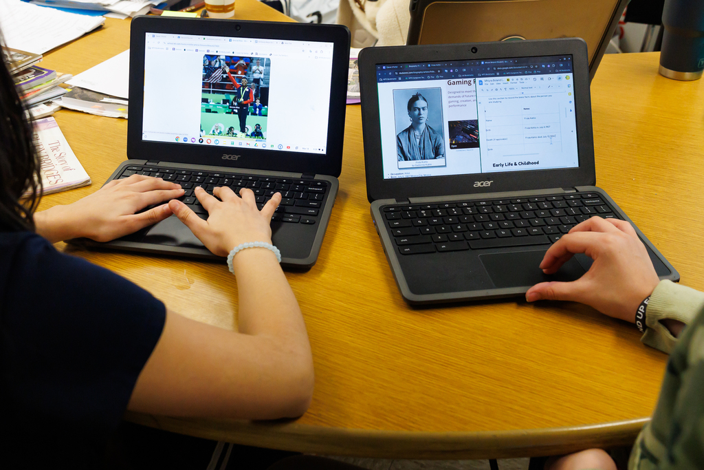 Students work on their laptops which display Simone Biles and Frida Kahlo.