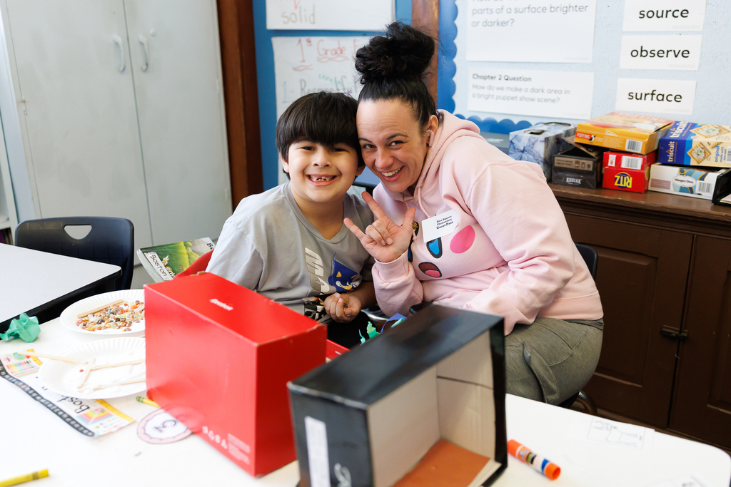 A parent and student pause from an activity to smile for a photo.