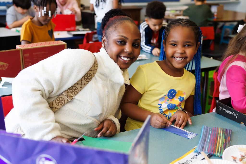 A parent and their child smile during an activity at school.