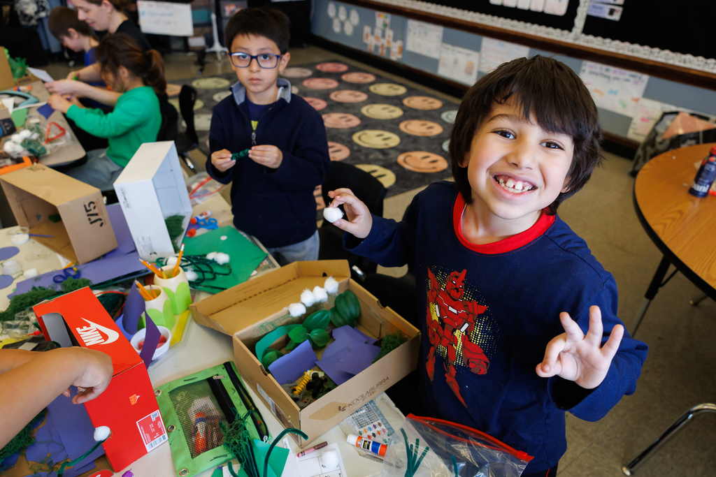 A student smiles during a habitat building activity at their school.