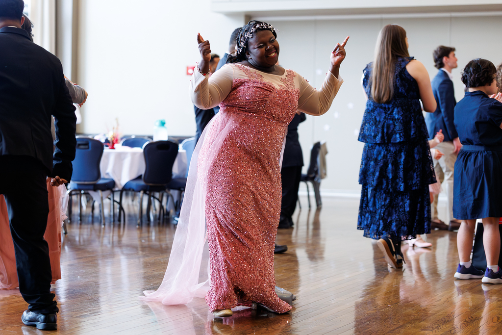 A student in a pink dress dances during a formal event.