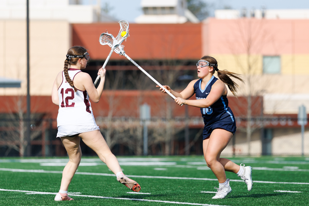 A lacrosse player defends an opposing player closely.