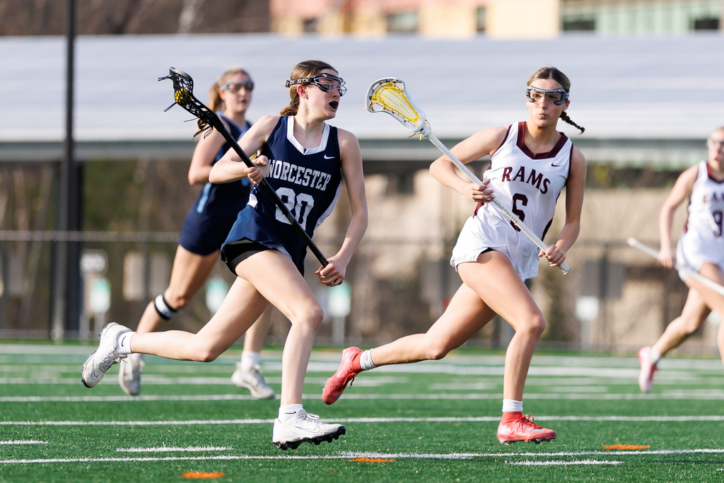 A lacrosse player runs through the defense with the ball on their stick.