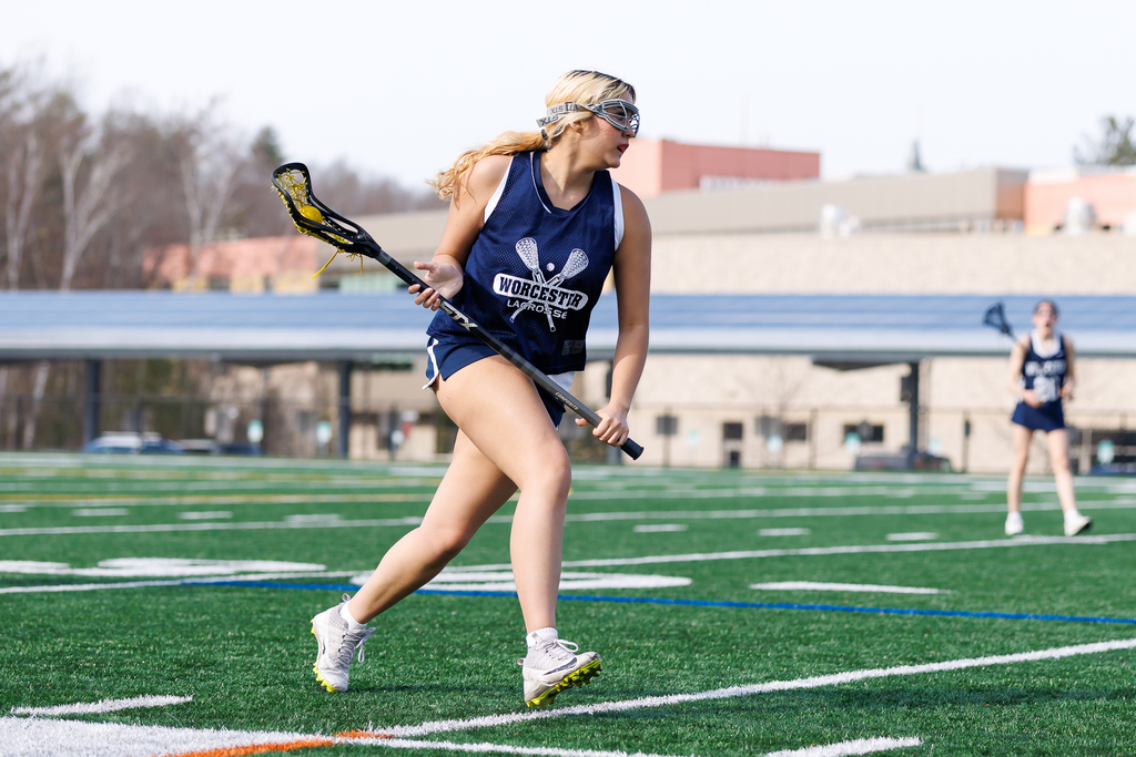 A lacrosse player runs with the ball on her stick during a game.