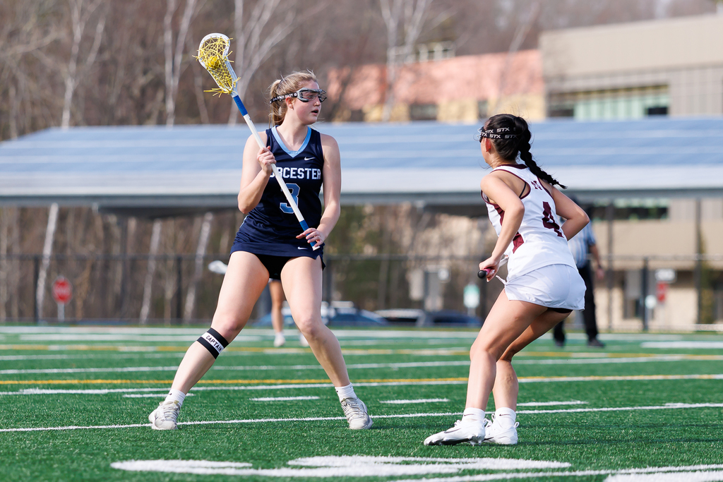 A lacrosse player looks to pass with a defender close by.