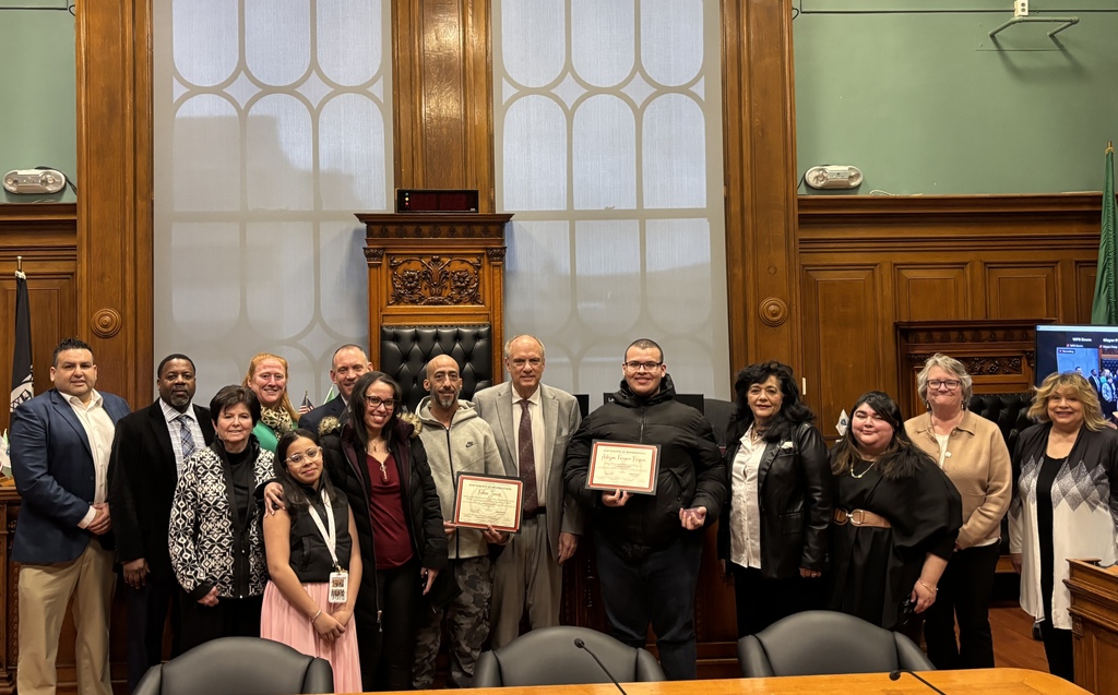 Public officials pose for a photo with a student and bus driver holding certificates