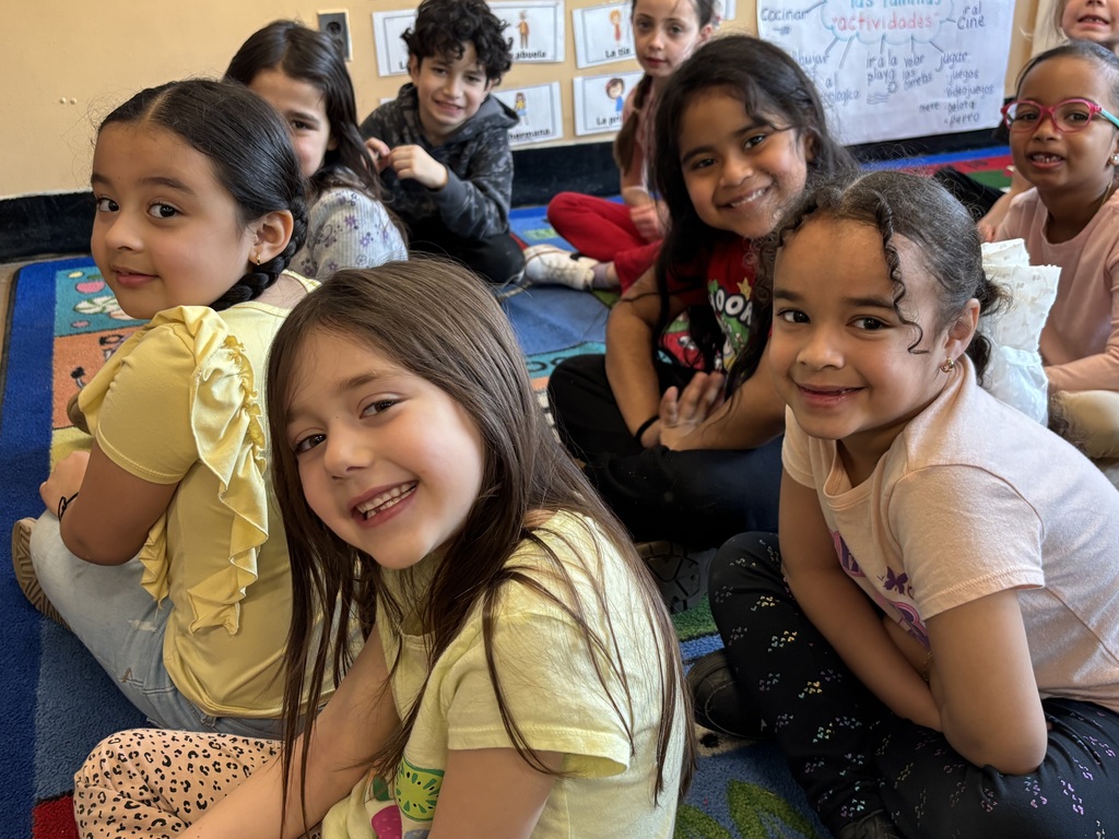 Smiling children sitting on a classroom rug