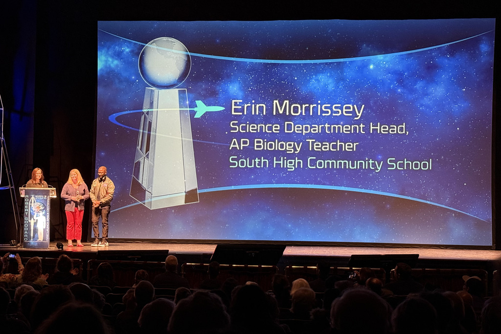 Erin Morrissey stands on stage to be awarded the Esther Goddard Teacher's Award.