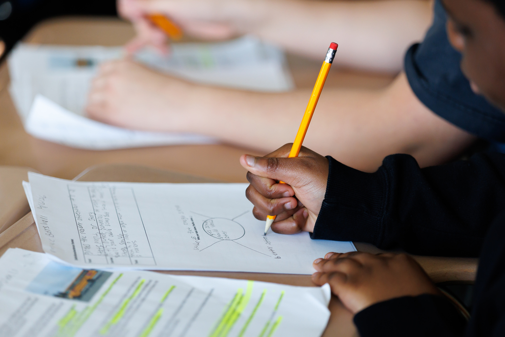 A student writes with a pencil. 