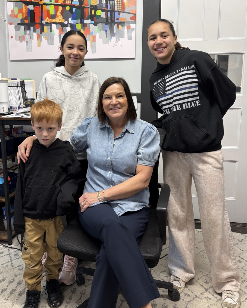 An administrative professional from Lake View School sits in a chair alongside three students.