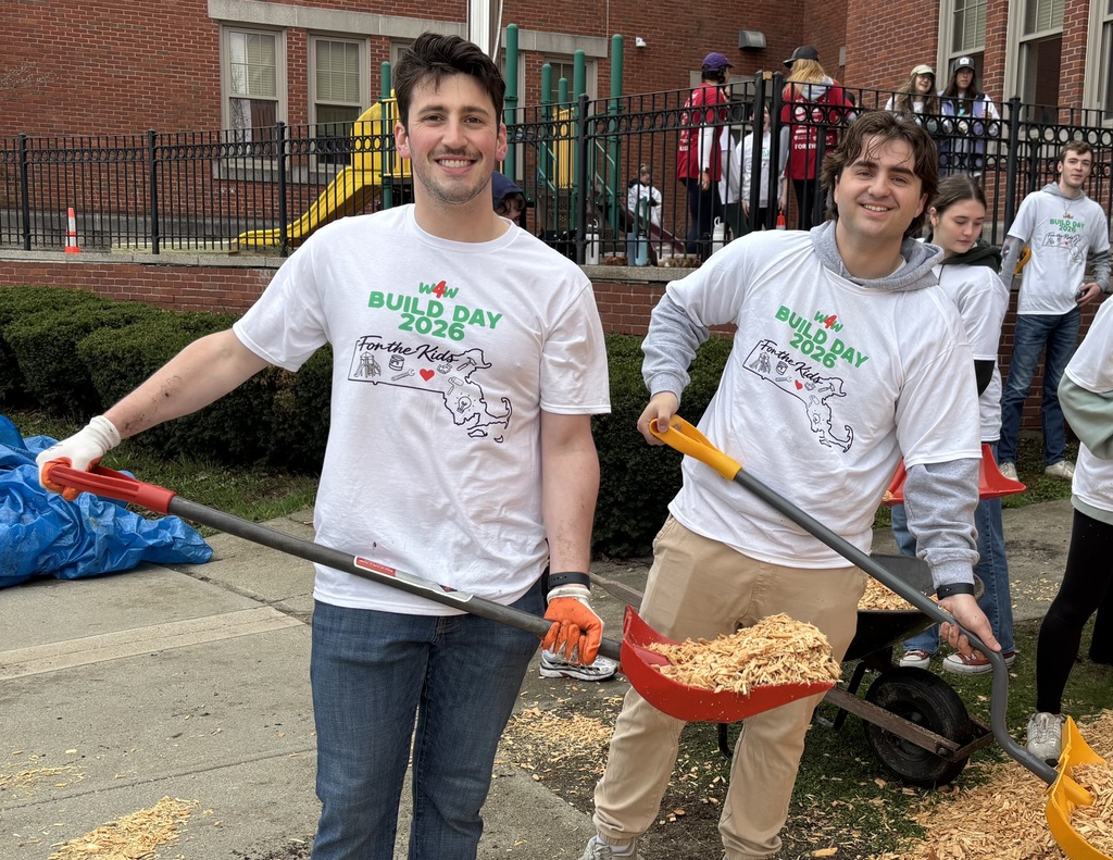Two young men holding shovels with mulch