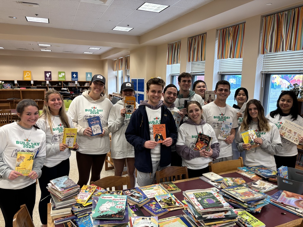A large group of volunteers pose for a photo while holding library books