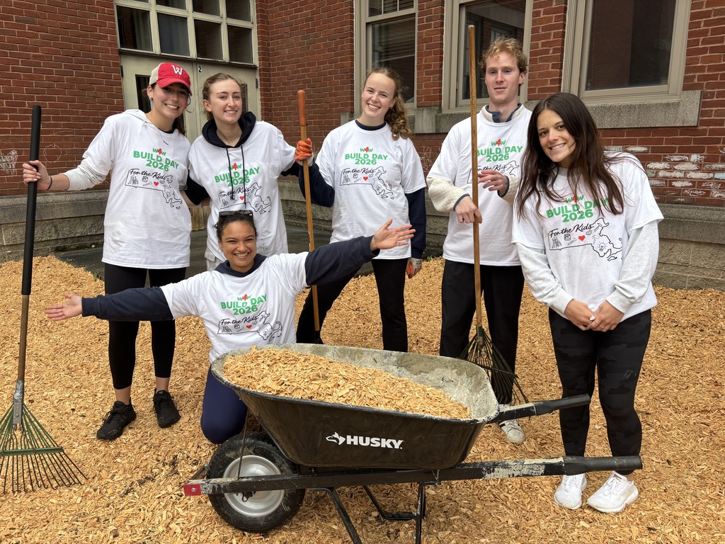 Six college students pose for a photo in front of a wheelbarrow