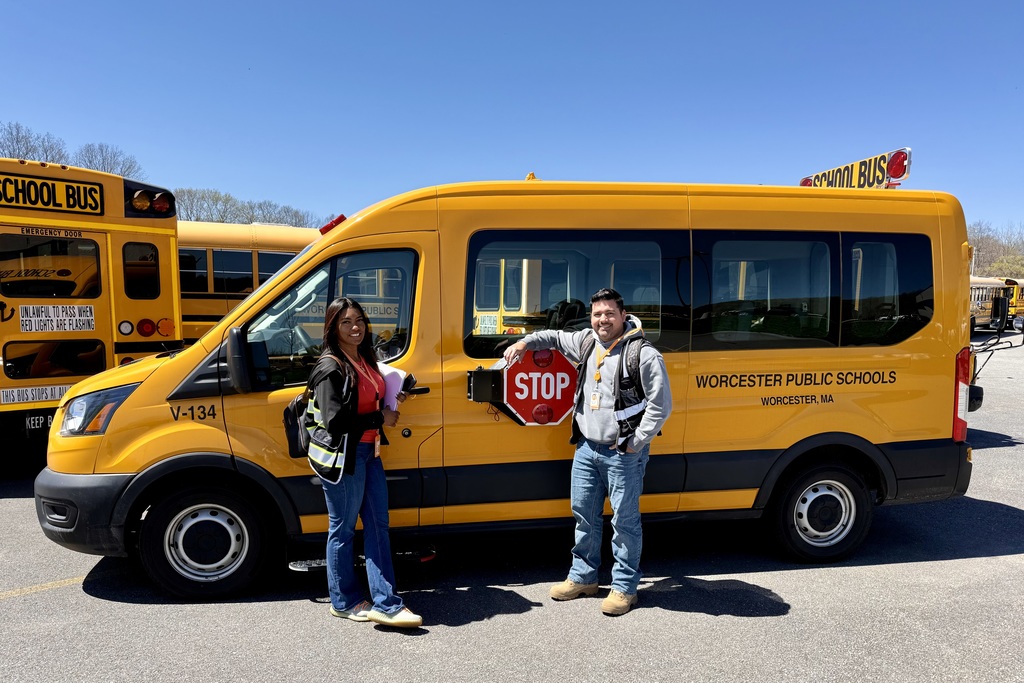 A woman and a man stand next to a yellow Worcester Public Schools bus.