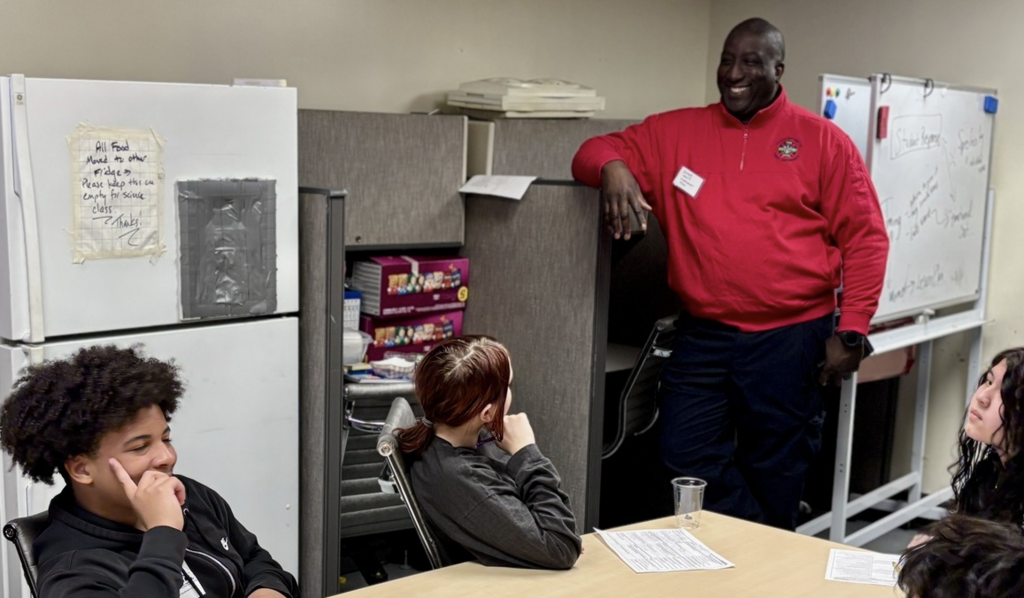 A professional standing in a classroom with students