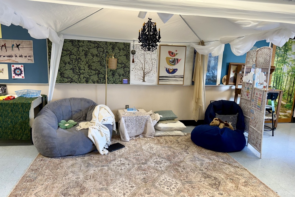 A cozy reading nook with large beanbag chairs, pillows, and a patterned rug under a tent-like canopy.