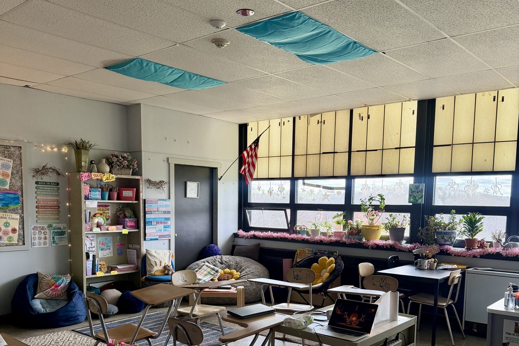 A classroom is decorated with inspirational posters, plants, and comfortable seating like beanbag chairs.