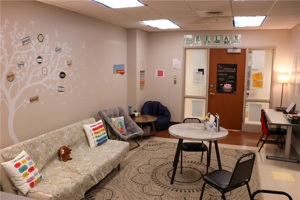 A calm waiting room with a couch, chairs, and a round table, decorated with inspirational wall art.