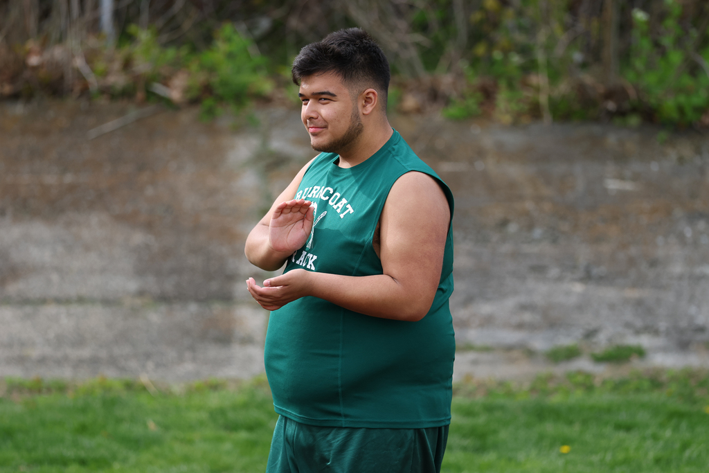 A student claps from the sidelines as they watch a track & field meet.
