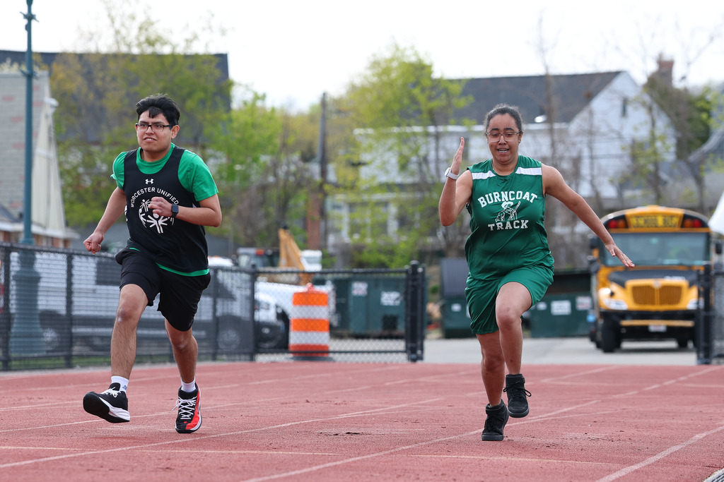 Two students run side by side during a track and field meet.