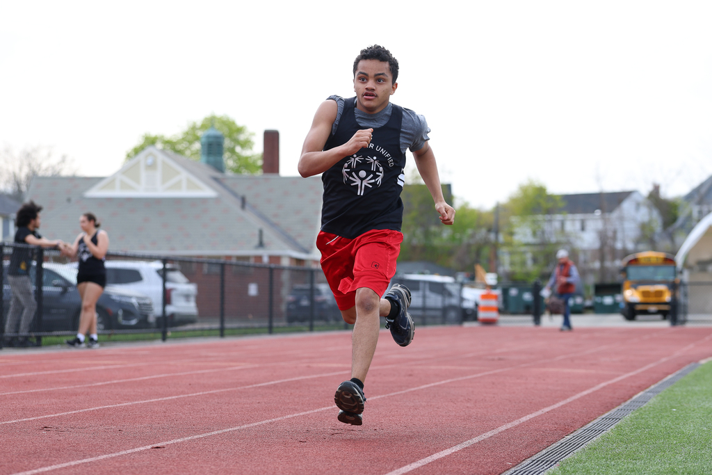A student runs on the track during a track & field meet.