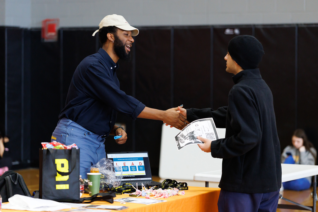 A business representative shakes the hands of a student during a career fair.