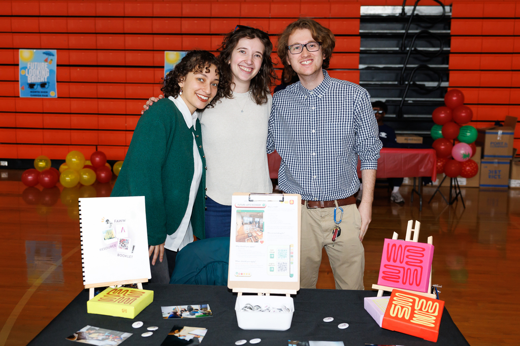 Three business representatives smile for a photo during a career day event.