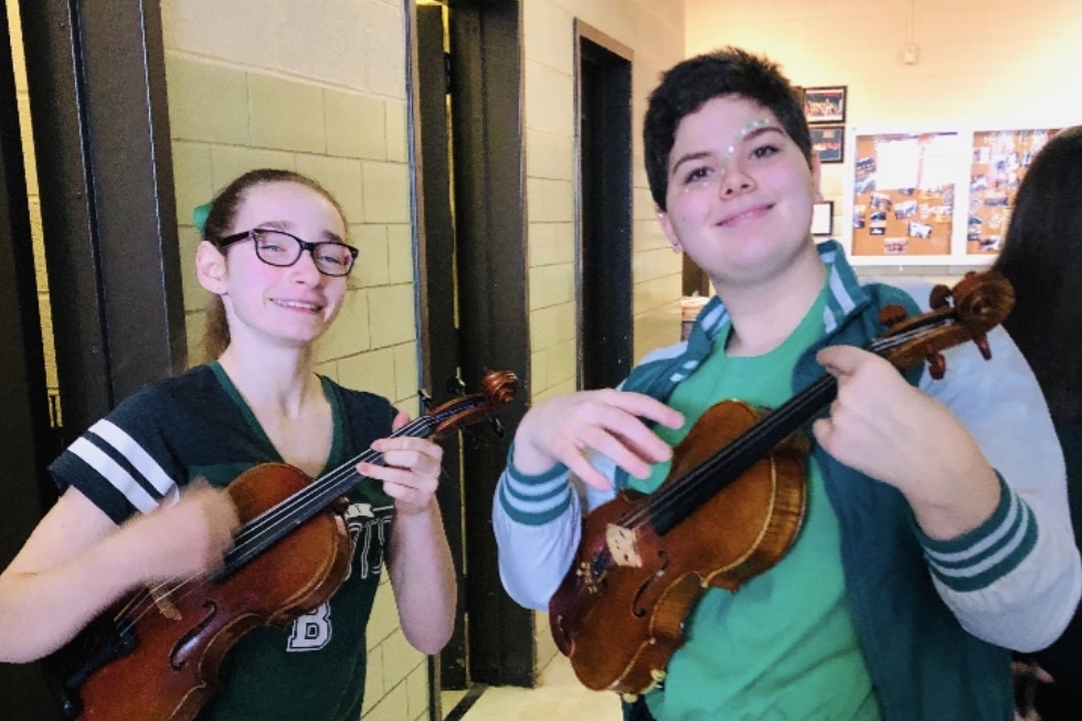 Jupiter Montalvo holds a violin alongside a classmate.