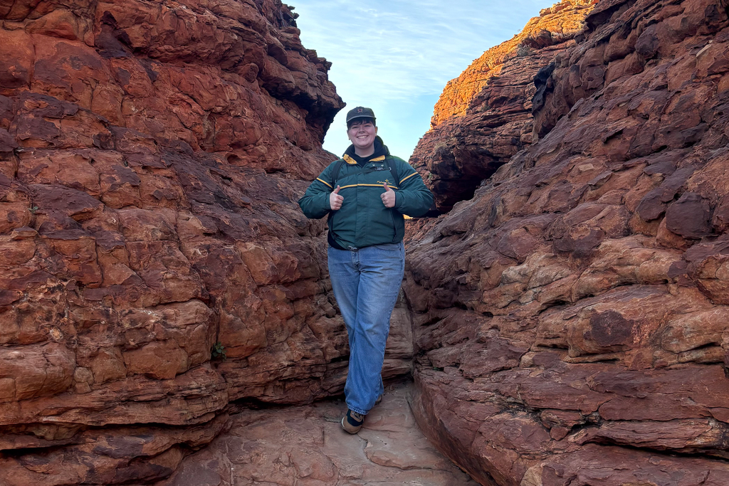 Jupiter Montalvo stands between two red rock boulders during a backpacking trip.