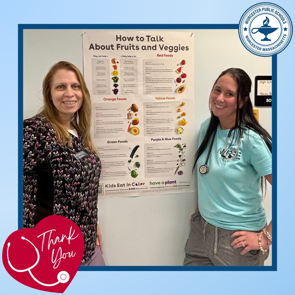 Two women stand in front of a poster titled 'How to Talk About Fruits and Veggies'.