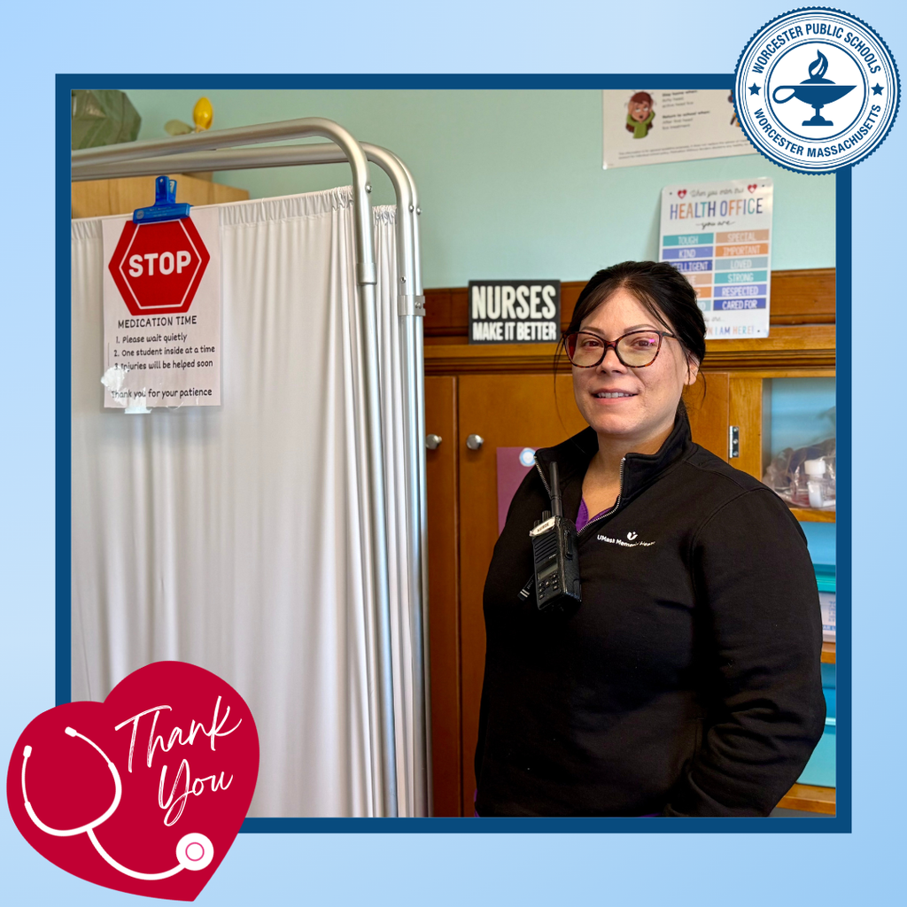 A nurse stands in a school health office, with a "Medication Time" sign and a "Nurses Make It Better" poster visible.