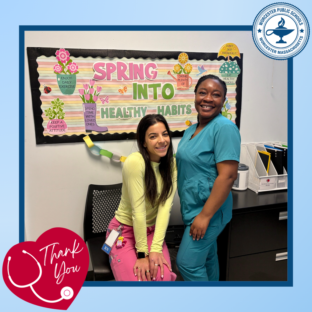 Two women smile in front of a bulletin board promoting "Spring Into Healthy Habits."