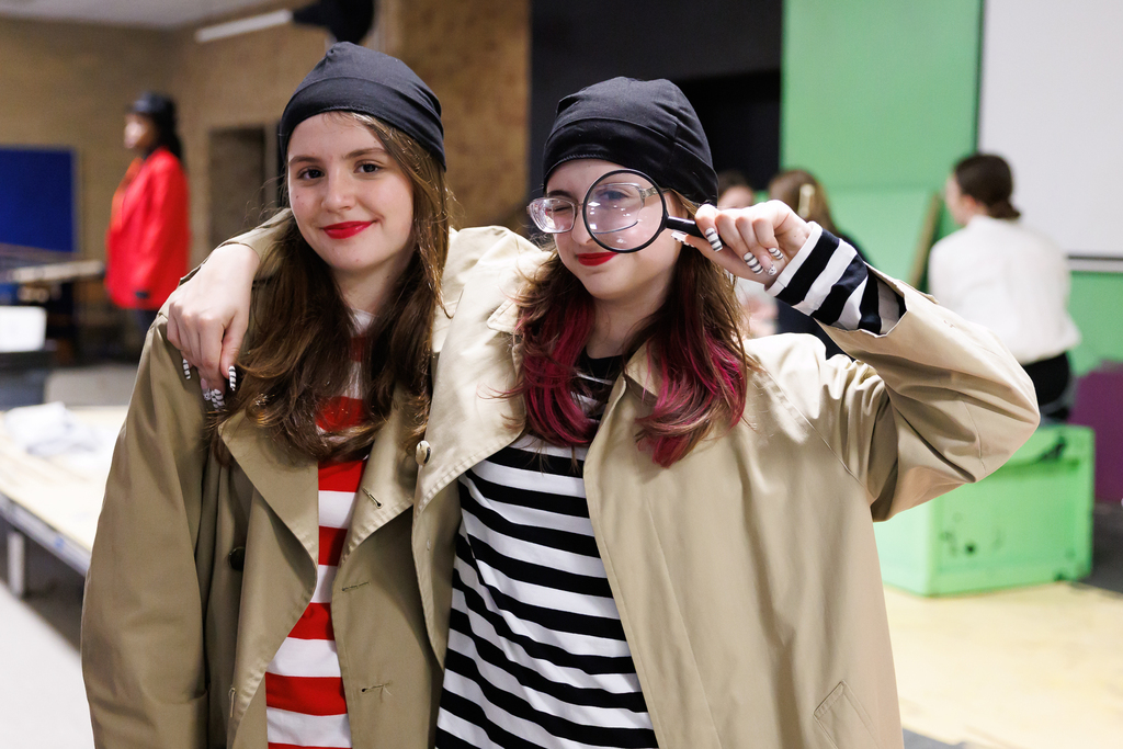 Two students stand together and smile for a photo while dressed in their costume for a play.