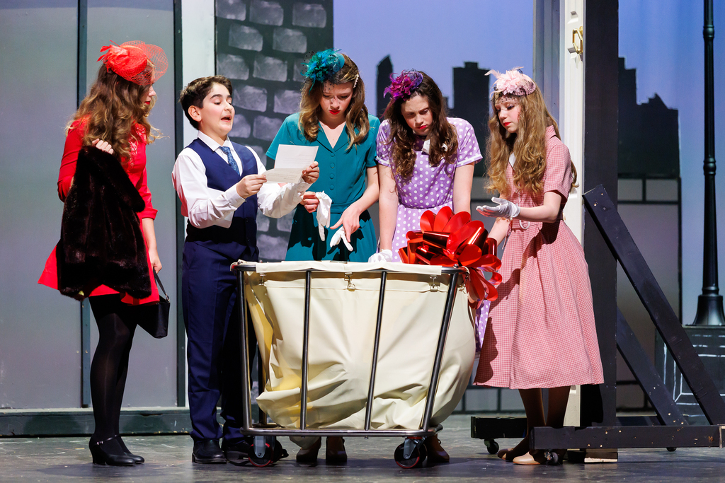 Five student actors stand behind a laundry basket during a play.