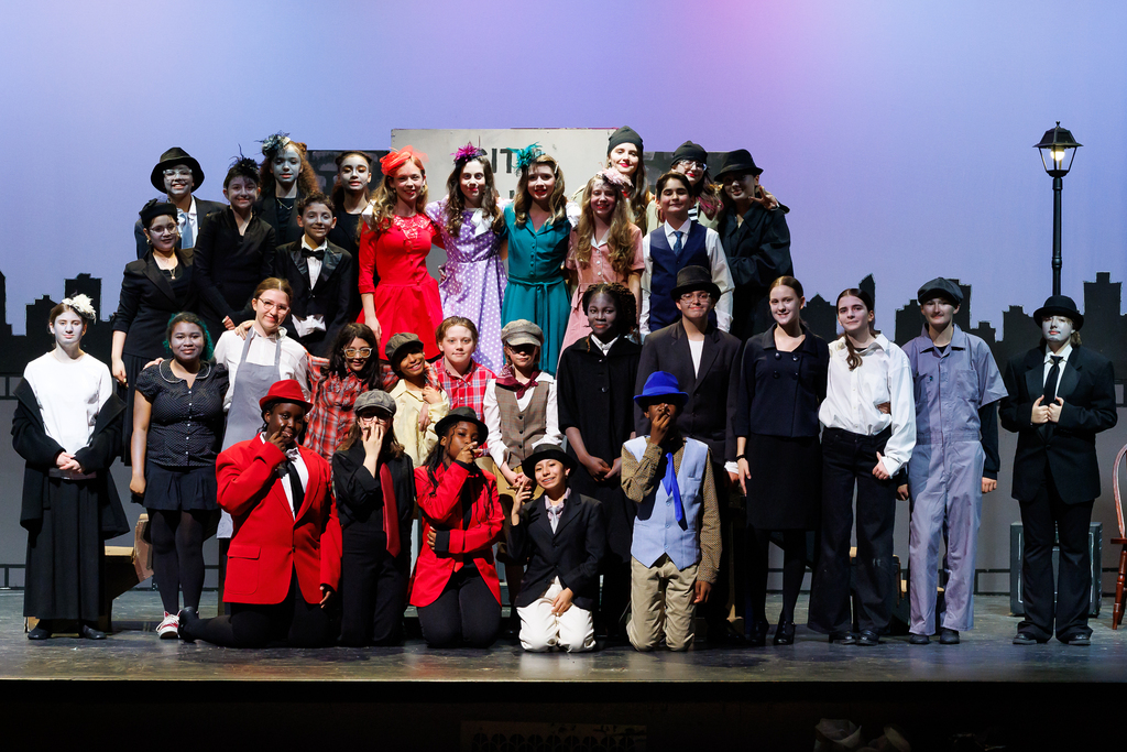 The cast and crew of Burncoat Middle School's Tough City, Prone to Rain stand on stage.