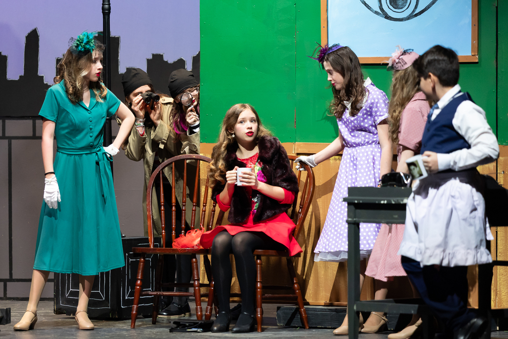Seven students perform on stage during a play.