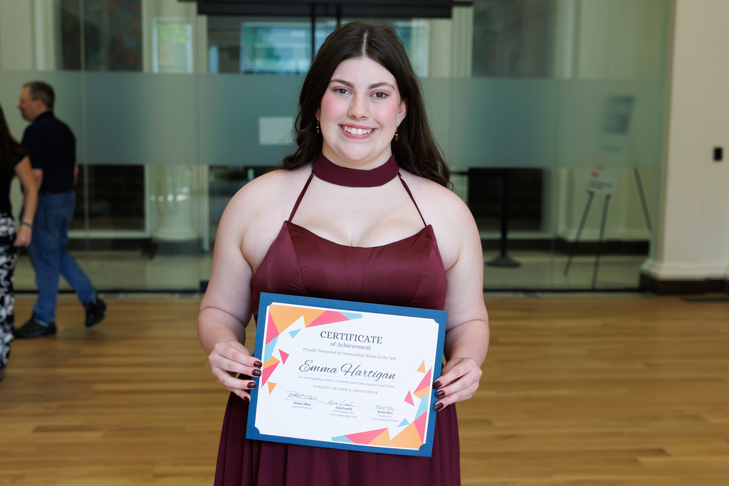 A student holds their award certificate.